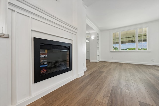 unfurnished living room with hardwood / wood-style flooring and ornamental molding