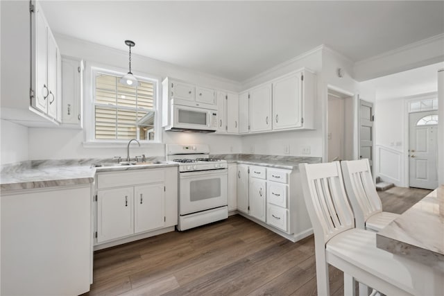 kitchen with hardwood / wood-style floors, white appliances, hanging light fixtures, sink, and white cabinets