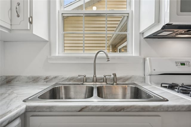 room details with white gas range oven, white cabinets, and sink