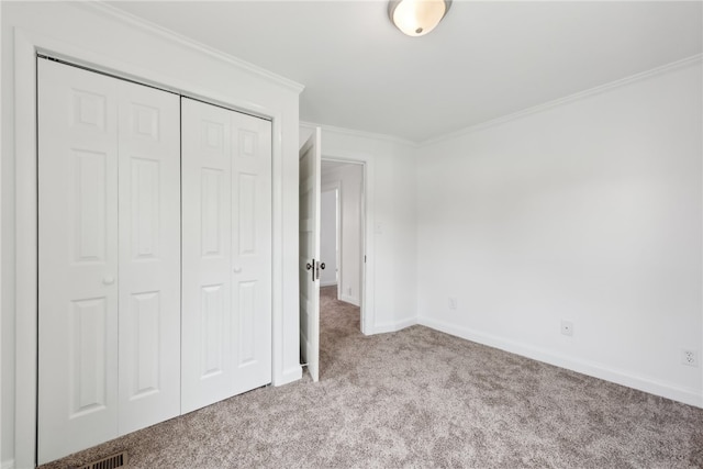 unfurnished bedroom with carpet, ornamental molding, and a closet