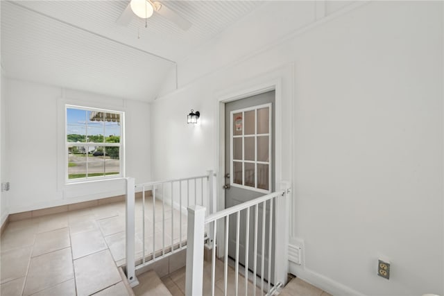 hallway featuring vaulted ceiling and light tile floors