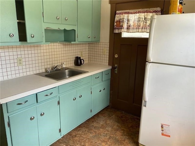 kitchen with white refrigerator, sink, dark tile floors, and backsplash