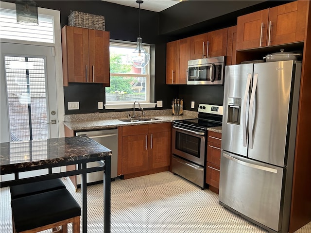 kitchen with light tile flooring, hanging light fixtures, stone counters, appliances with stainless steel finishes, and sink