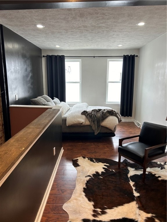 bedroom with dark hardwood / wood-style floors and a textured ceiling