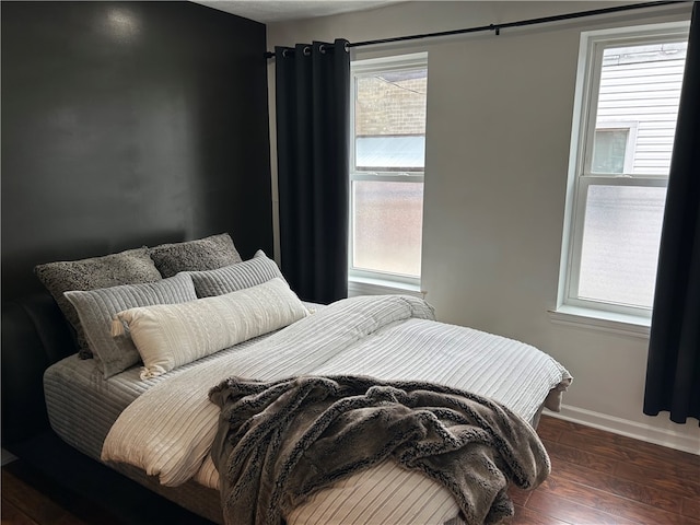 bedroom featuring multiple windows and dark wood-type flooring