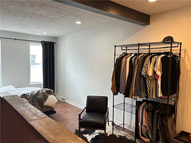 interior space with beamed ceiling, a textured ceiling, and wood-type flooring