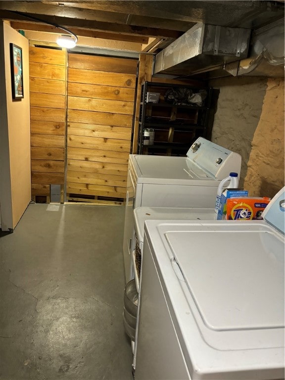 laundry room featuring washer and dryer and wood walls