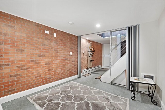 workout room featuring baseboard heating and brick wall