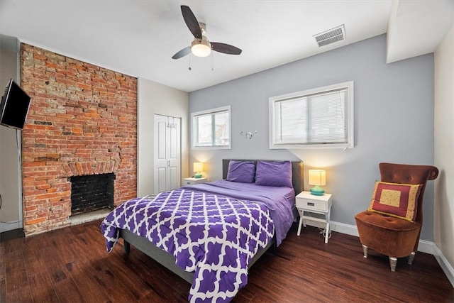 bedroom with a fireplace, ceiling fan, a closet, and dark hardwood / wood-style floors