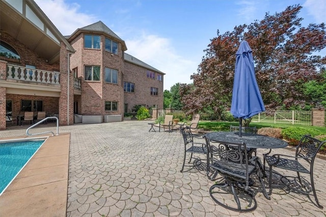 view of patio with a fenced in pool and a balcony