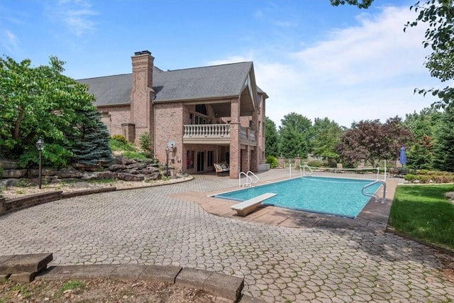 view of swimming pool featuring a diving board and a patio