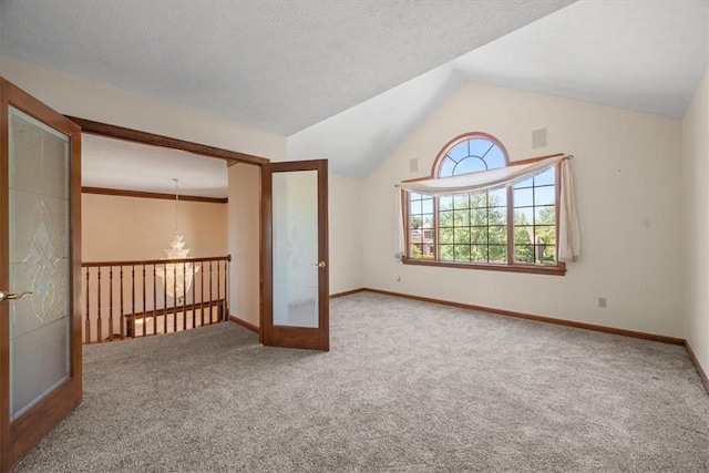 carpeted empty room featuring an inviting chandelier, lofted ceiling, a textured ceiling, and french doors