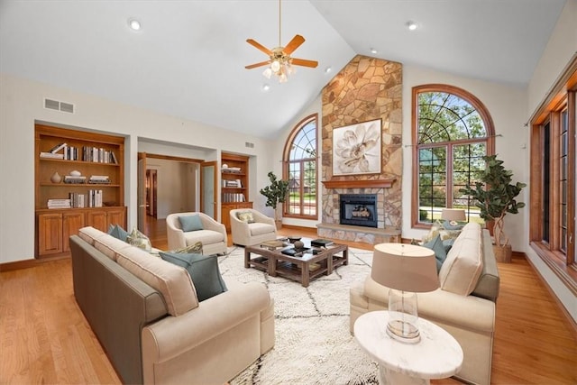 living room with a fireplace, light wood-type flooring, built in features, and ceiling fan