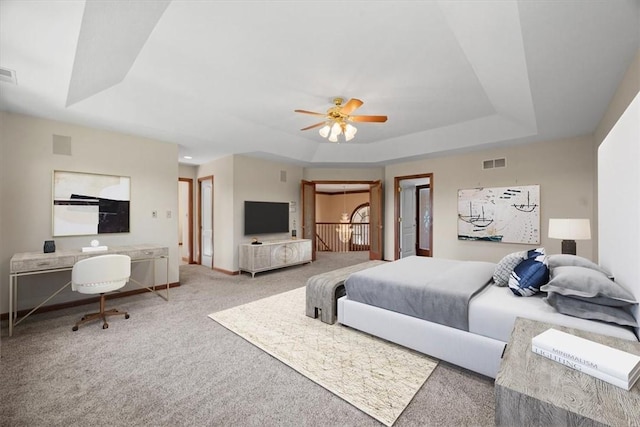 carpeted bedroom featuring a tray ceiling and ceiling fan