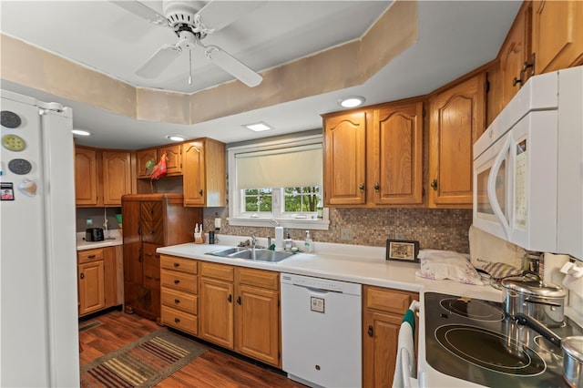 kitchen with white appliances, ceiling fan, a raised ceiling, and dark hardwood / wood-style flooring