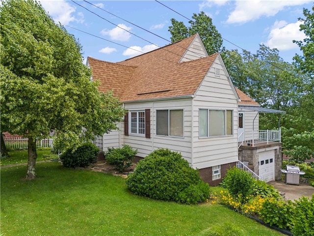 view of front of property featuring a garage, a balcony, and a front lawn