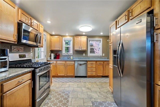 kitchen featuring light stone counters, stainless steel appliances, and sink