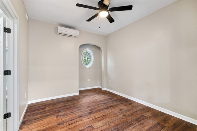 empty room with dark wood-type flooring, ceiling fan, and an AC wall unit