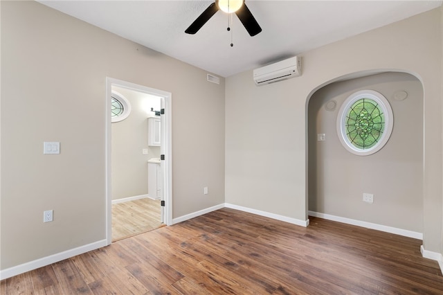 unfurnished room with an AC wall unit, ceiling fan, and hardwood / wood-style floors