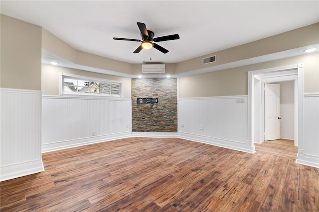 spare room with a wall mounted AC, ceiling fan, and hardwood / wood-style floors