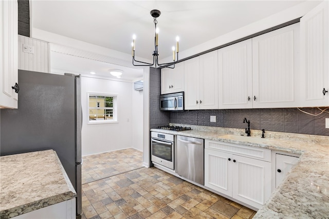 kitchen featuring a chandelier, stainless steel appliances, tasteful backsplash, white cabinets, and sink