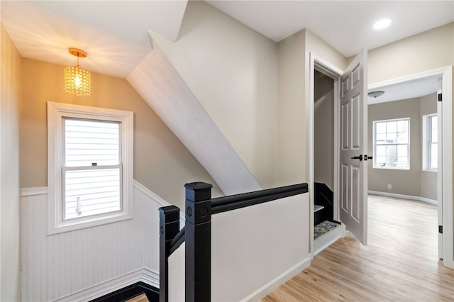 corridor featuring a chandelier, vaulted ceiling, and light hardwood / wood-style flooring