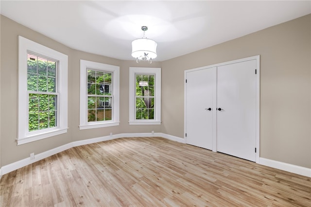 unfurnished bedroom with a closet, light wood-type flooring, and an inviting chandelier