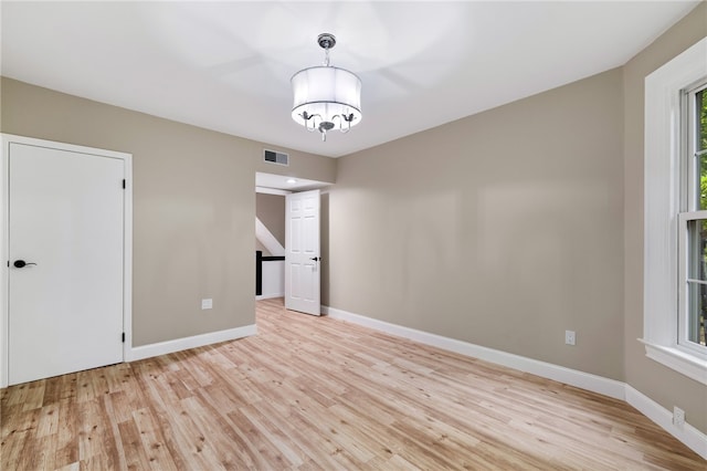 spare room featuring an inviting chandelier and light hardwood / wood-style flooring