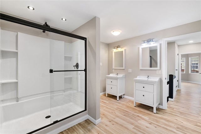 bathroom with a shower with shower door, double sink vanity, and hardwood / wood-style floors