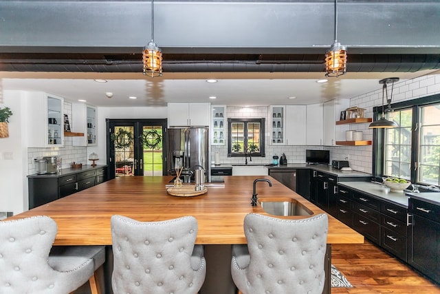 kitchen with backsplash, hanging light fixtures, white cabinetry, and stainless steel fridge with ice dispenser