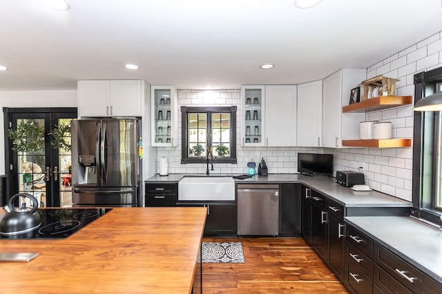 kitchen featuring stainless steel appliances, backsplash, hardwood / wood-style floors, white cabinets, and sink