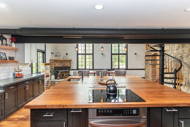 kitchen with light hardwood / wood-style floors, black electric cooktop, wooden counters, sink, and tasteful backsplash