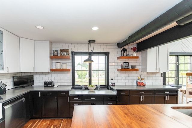 kitchen with tasteful backsplash, white cabinets, decorative light fixtures, and stainless steel dishwasher