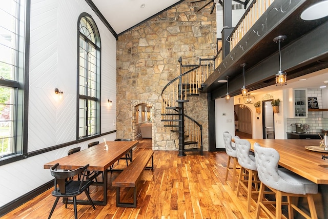 dining room featuring high vaulted ceiling, ornamental molding, and hardwood / wood-style floors