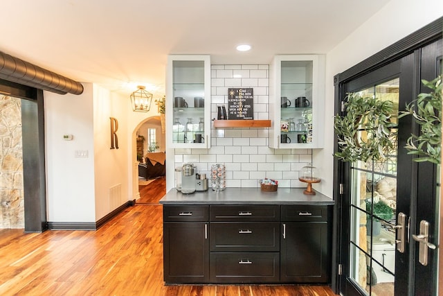 bar with backsplash and light hardwood / wood-style flooring