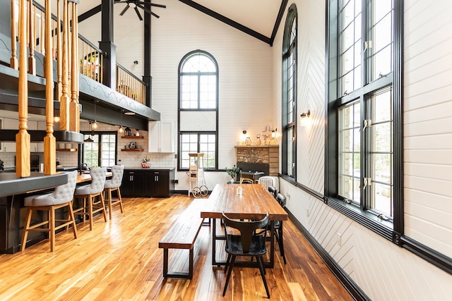 dining space with high vaulted ceiling and light hardwood / wood-style floors