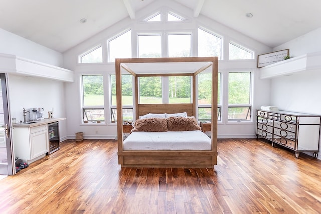 bedroom with wine cooler, high vaulted ceiling, light hardwood / wood-style flooring, and beamed ceiling