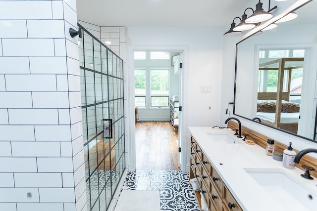 bathroom featuring a shower with shower door, double vanity, and plenty of natural light