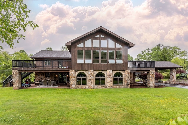 back of property featuring a deck, a lawn, and a patio