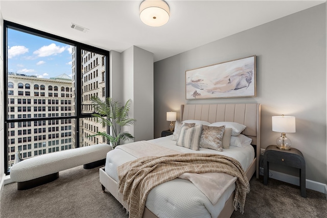 bedroom featuring a wall of windows and dark carpet