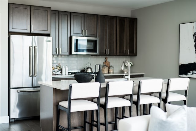 kitchen featuring appliances with stainless steel finishes, dark brown cabinets, and tasteful backsplash