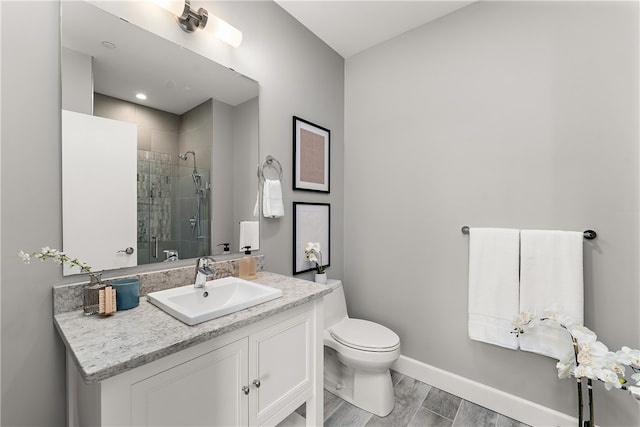 bathroom featuring tiled shower, oversized vanity, hardwood / wood-style flooring, and toilet