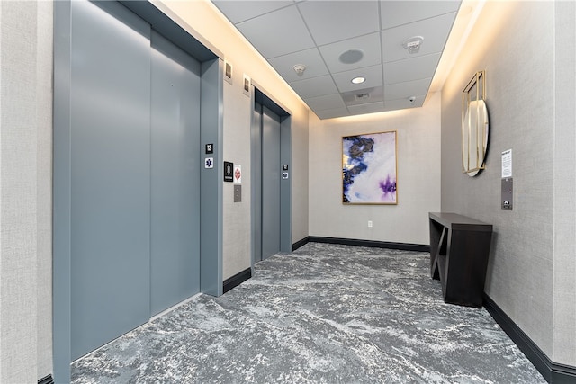 hall with elevator and a paneled ceiling