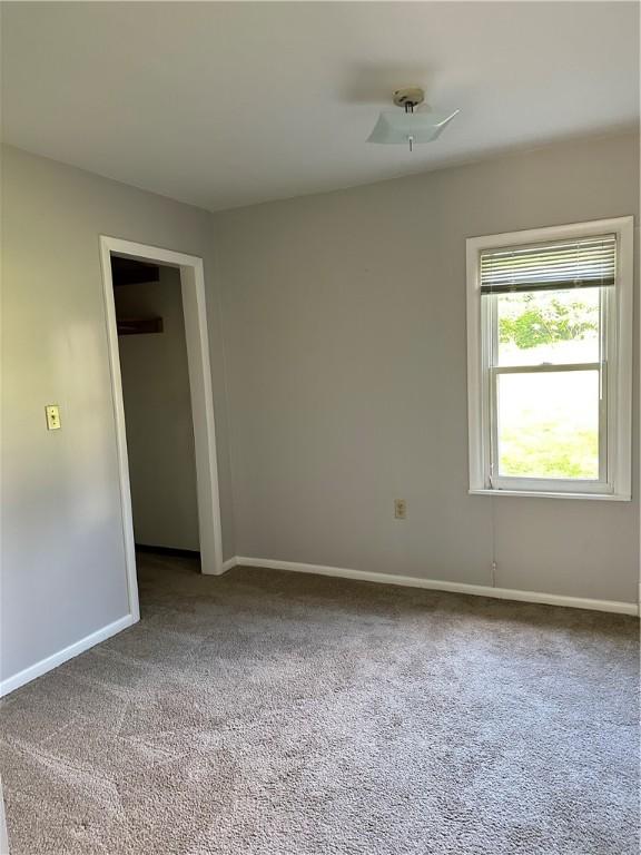 carpeted spare room featuring ceiling fan