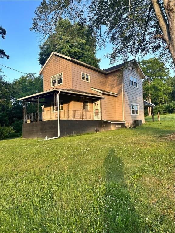 rear view of house featuring a porch and a yard