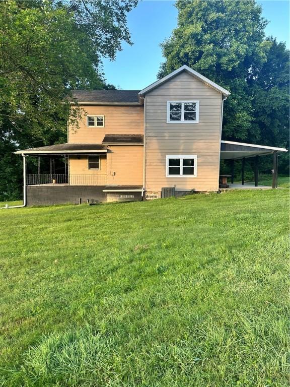 view of home's exterior with a carport, central AC unit, and a yard