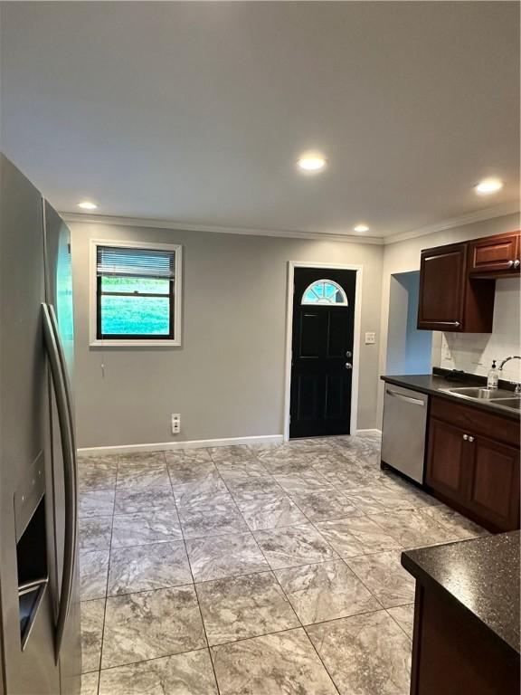 kitchen with sink, stainless steel appliances, tasteful backsplash, crown molding, and dark brown cabinets