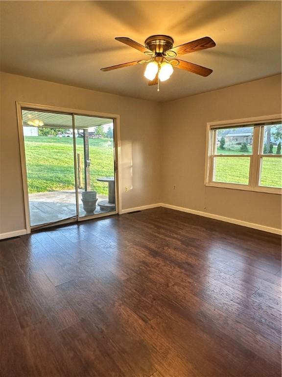 empty room featuring ceiling fan, dark hardwood / wood-style floors, and plenty of natural light