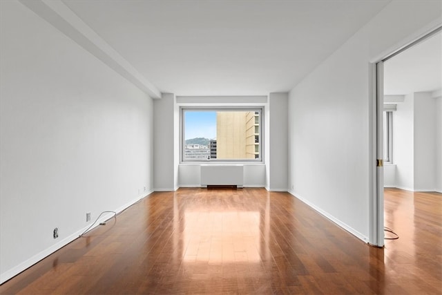 empty room with wood-type flooring and radiator heating unit