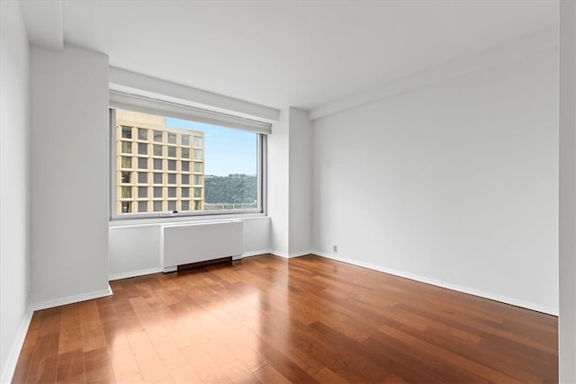 empty room with wood-type flooring and radiator